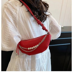 Dettaglio borsa a mezzaluna intrecciata rossa con perle e decorazioni a catena