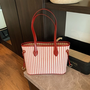 Close-up of red and white striped canvas tote bag with leather handles on stone counter