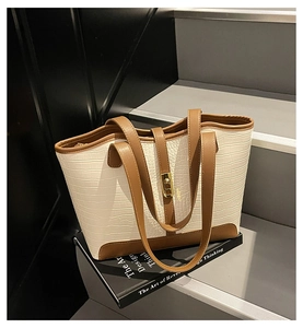 Detail view of crocodile pattern tote bag with gold metal lock and brown leather trim