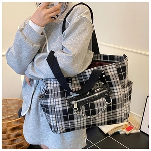 Detail of gothic punk plaid tote bag featuring silver rivets and metal chain accents