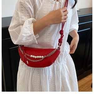 Detail of red woven dumpling bag featuring silver chain and large white pearl accents