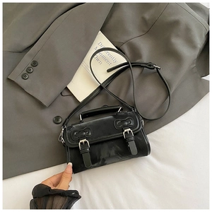 Détail du sac cartable en cuir noir avec boucles en métal et poignée supérieure
