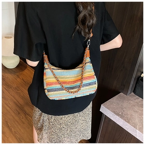 Detail of colorful woven shoulder bag with wavy stripes and metal chain strap decoration