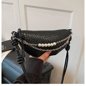 Close-up of black woven dumpling bag with gold chain and pearl embellishments