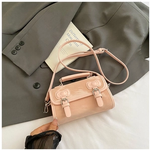 Détail du sac en cuir verni rose montrant le relief de nœud 3D et boucles argentées