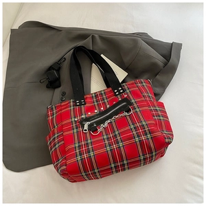 Detail of red plaid punk tote bag with silver metal chains and zippers on canvas