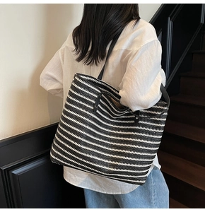Close-up of a large black and white striped tote bag with leather shoulder straps