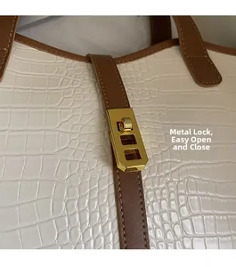Close-up of golden rectangular metal buckle on a white crocodile embossed tote bag