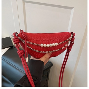 Detailed macro view of red woven crescent bag with decorative gold chains and faux pearls