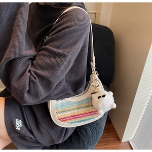 Detail of colorful rainbow woven crossbody bag with white leather strap and plush charm
