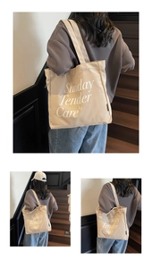 Vista detallada de un bolso shopper grande de lona beige con letras blancas para uso diario
