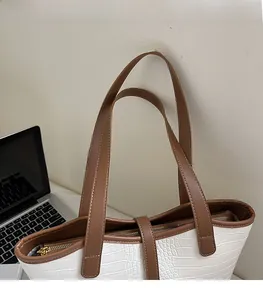 Detail of crocodile embossed faux leather tote bag with brown trim and gold metal zipper
