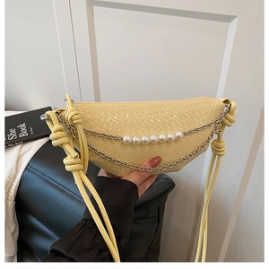 Detail of light yellow woven bag with golden chain and pearl accents on the strap