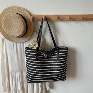 Close-up of black and white striped woven tote bag with durable leather straps