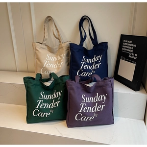 Dettaglio di grandi borse tote in tela nei colori beige, blu navy, verde e viola