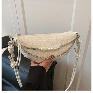 Close-up of woven cream moon bag with elegant pearl chain and knotted shoulder strap