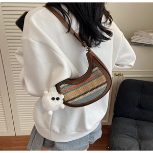 Detail view of rainbow woven crossbody bag with brown leather trim and plush pendant