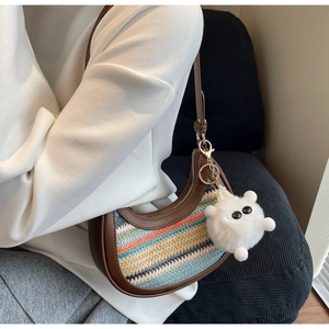 Rainbow woven half-moon bag with brown leather trim and a white plush monster charm