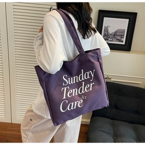 Detalle del bolso tote de lona morada con diseño de letras blancas Sunday Tender