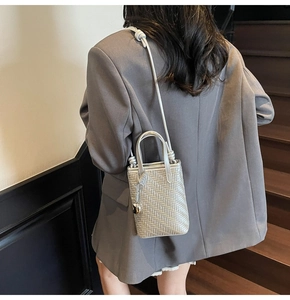 Metallic silver mini tote bag with woven texture worn by model on stairs