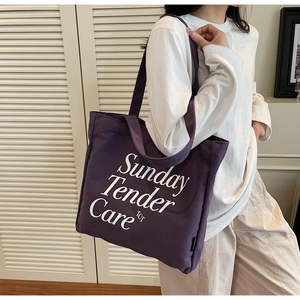 Detalle del bolso tote de lona morada con estampado de letras Sunday Tender Care TCT