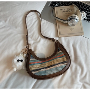 Detail of rainbow woven crossbody bag with brown leather trim and white plush charm