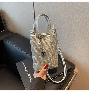 Detailed view of silver woven texture and metallic charm on mini crossbody bag
