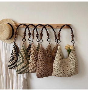 Detail of woven beach tote with intricate hollow crochet pattern and wooden bead handle