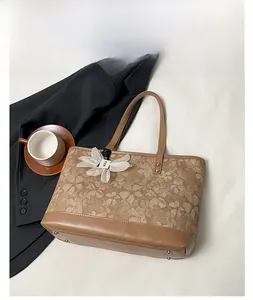 Detail of khaki floral canvas tote with premium leather handles and flower charm