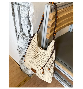 Detail of beige crochet bucket bag with wooden bead straps and woven mesh texture