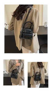 Detail of a black mini crossbody bag with silver hardware and a top handle on a beige suit