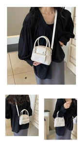 Detailed view of a mini white glossy handbag featuring silver hardware and a slim shoulder strap