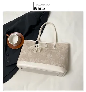 Detail view of large white tote bag with floral jacquard fabric and metal feet