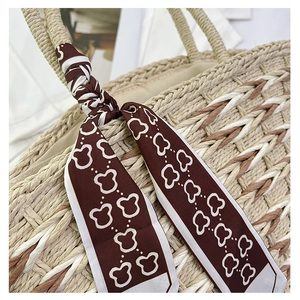 Detail of woven straw handbag with brown printed scarf and intricate fiber textures