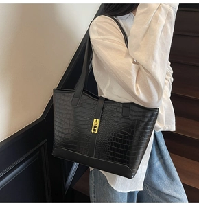Detailed macro view of black crocodile pattern texture and gold buckle on a tote bag