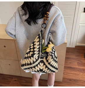 Detail of woven tote bag featuring black geometric patterns and unique dark wood bead straps