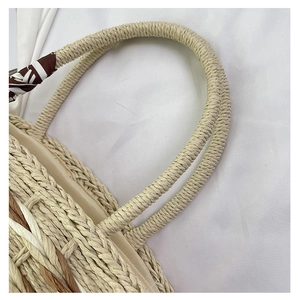 Detail of hand-woven straw bag with striped silk scarf handle and beige fabric lining