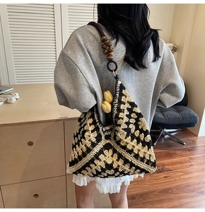 Detail of hand-woven hobo bag featuring contrast crochet patterns and brown wooden beads