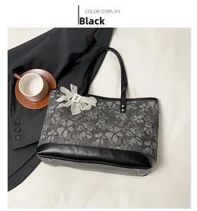 Detail view of floral tote bag with black leather base and metallic bottom rivets