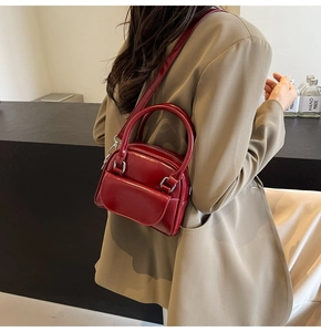 Detail of dark red patent leather square bag styled with a khaki blazer for a chic look
