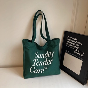 Primer plano del bolso tote de lona verde oscuro con letras blancas de Sunday