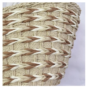 Detailed close-up of woven straw handbag featuring beige fibers and brown textured straps