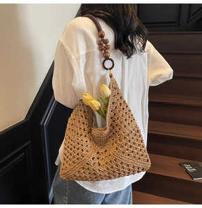 Detailed back view of a hollow woven straw shoulder bag with wooden bead strap