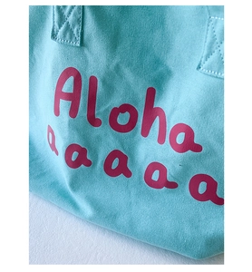 Close-up of durable canvas stitching and Aloha print on turquoise tote bag