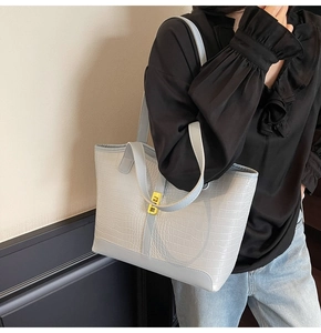 Close-up of crocodile pattern texture and gold buckle on a grey tote bag