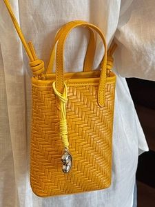 Minimalist yellow woven crossbody bag with metal bean charm and knotted strap