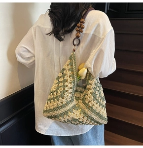 Detail of hand-woven shoulder bag with green geometric patterns and wooden beads