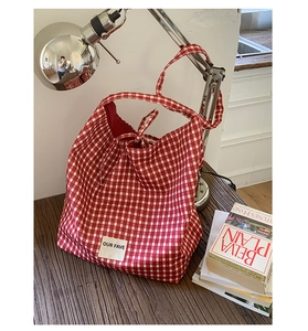 Macro shot of red gingham canvas tote bag with tie closure and white woven label