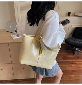 Detailed view of beige faux-crocodile tote bag with elegant golden metal clasp