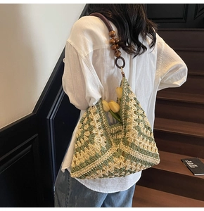 Detail of hand-woven shoulder bag with green diamond pattern and wooden beads